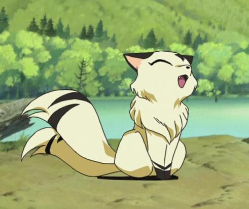 Na imagem, vemos Kirara, uma espécie de felino do anime Inuyasha. Ela tem a cor dourada com faixas pretas em sua cauda e patas assim como suas orelhas. Kirara está de pé com suas duas caudas com um rosto muito feliz como se tivesse sido agradada.