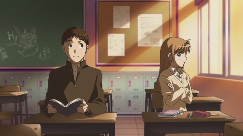 Takashi Kosuda e Yamada sentados dentro de uma sala de aula aparentemente vazia, ambos se olhando discretamente.