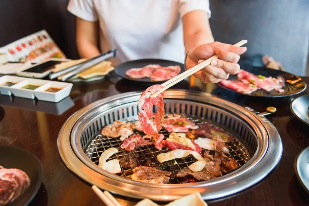 Foto de uma mesa de jantar coberta por pratos com yakiniku, o churrasco japonês originado da coreia depois dos tempos de guerra no século XX