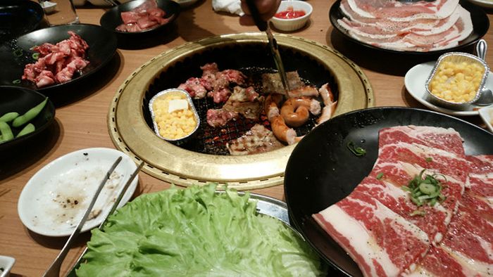 Foto de uma churrasqueira de mesa contendo alguns pedaços de yakiniku